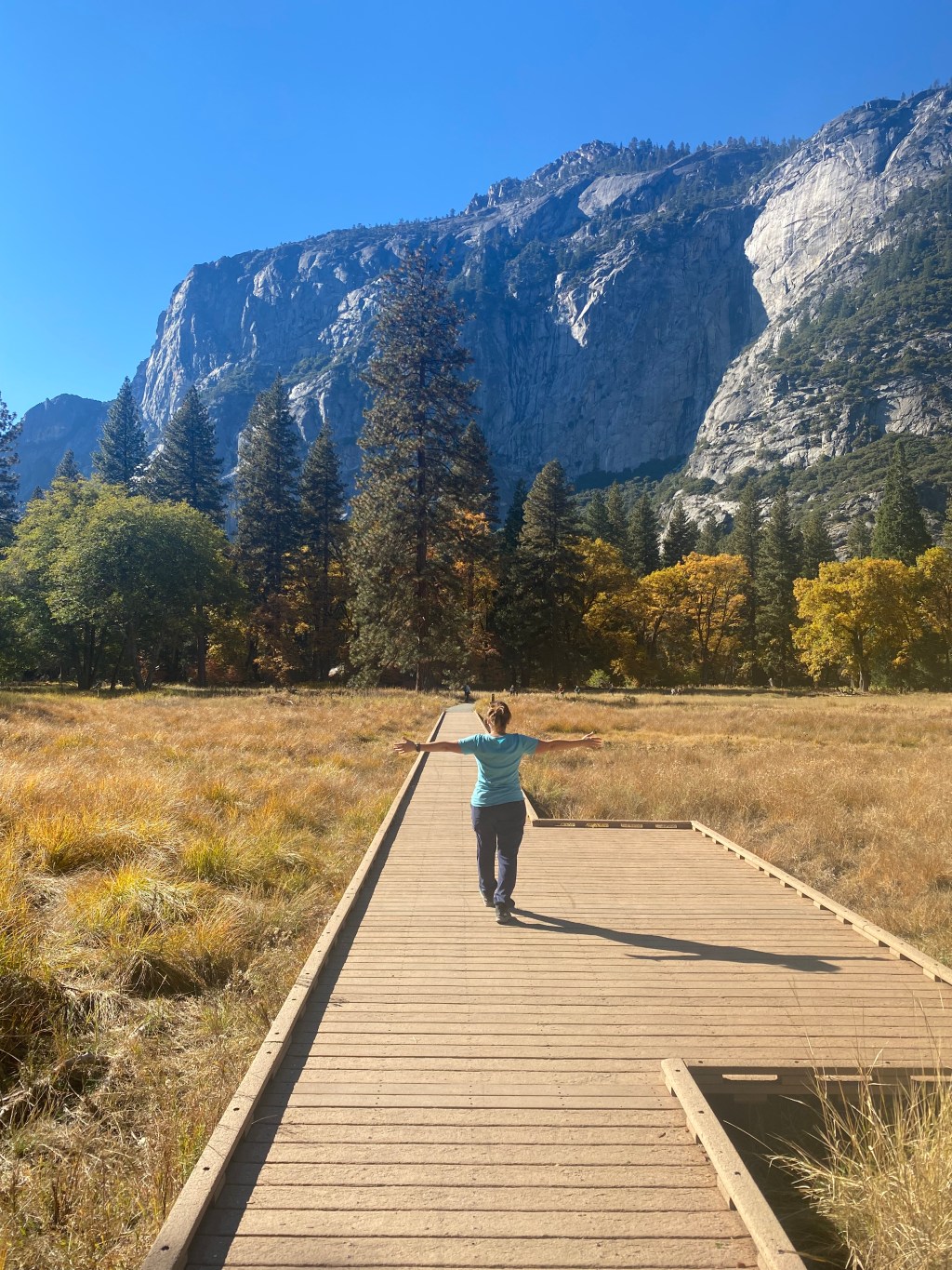 Woman walking toward mountains with arms outstretched, symbolizing healing and renewal after postpartum thyroid issues.